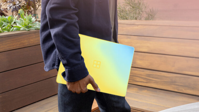 A man walks through a lobby carrying a Microsoft Surface tablet
